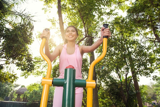 Uśmiechnięta azjatykcia kobieta robi treningowi na elliptical maszynie