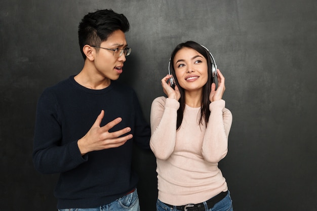 Uśmiechnięta beztroska azjatycka kobieta słuchająca muzyki przez słuchawki