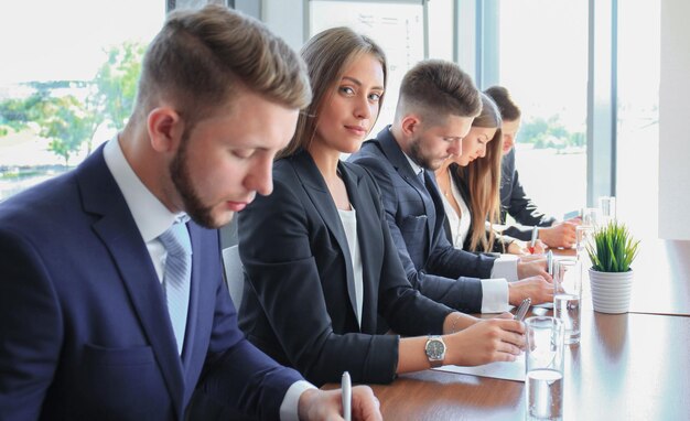 Zdjęcie uśmiechnięta bizneswoman patrząca na kamerę na seminarium z kolegami w pobliżu