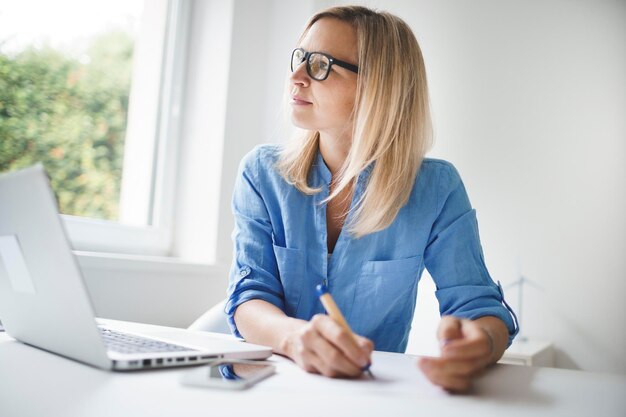 Uśmiechnięta bizneswoman pisząca na dokumencie w biurze