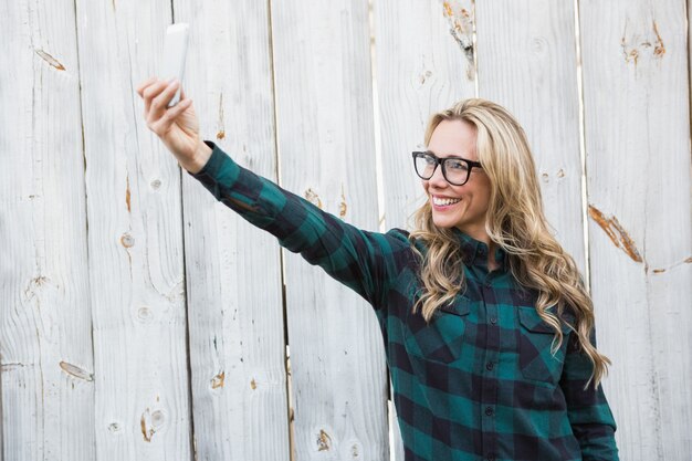 Uśmiechnięta blondynka z szkłami bierze selfie