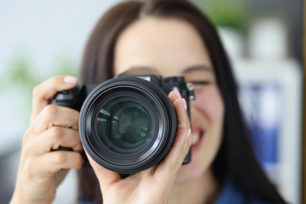 Uśmiechnięta brunetka fotografka wskazująca na ciebie superszerokokątny obiektyw