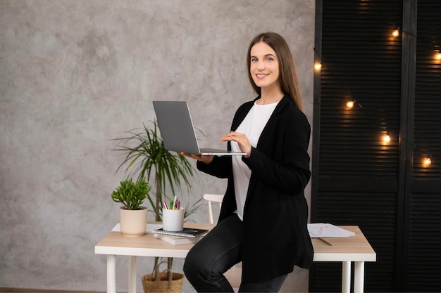 Uśmiechnięta brunetka kobieta korzysta z laptopa na szarym tle