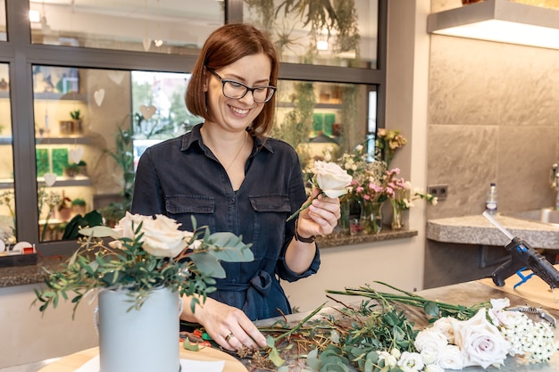 Uśmiechnięta brunetka kobieta zbieranie pudełko kwiat. Kwiaciarz. Warsztaty florystyczne. Koncepcja nauczania klasy mistrzowskiej.