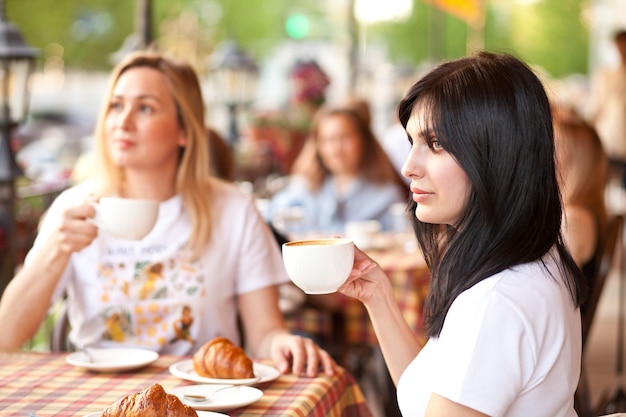 Uśmiechnięta Brunetki Kobieta Pije Kawę Z Przyjaciółmi Przy Kawiarni. Koncepcja Komunikacji I Przyjaźni.