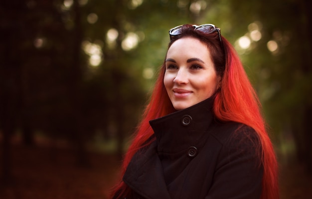 Uśmiechnięta czerwona włosiana kobieta w jesień parku