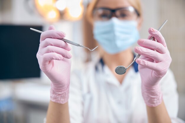 Uśmiechnięta dentystka używająca instrumentów w biurze