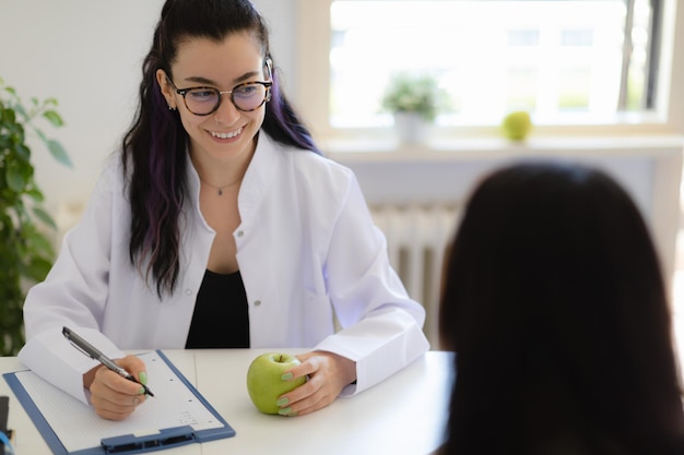 Zdjęcie uśmiechnięta dietetyk-lekarz udzielający konsultacji na temat planu diety i zdrowego odżywiania, aby pomóc pacjentowi schudnąć
