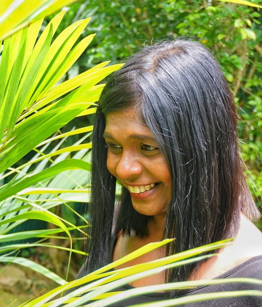 Zdjęcie uśmiechnięta dojrzała kobieta stojąca przy roślinach