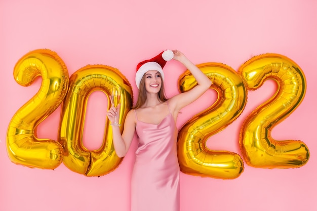 Uśmiechnięta Dorosła Dziewczyna Trzyma Kieliszek Szampana W Santas Hat Złote Balony Na Nowy Rok Koncepcja