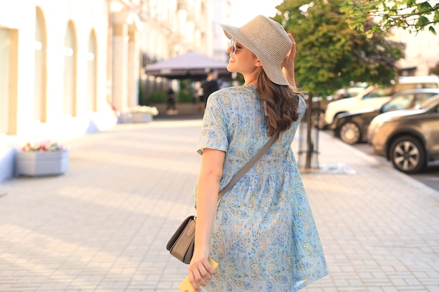 Uśmiechnięta dziewczyna modny hipster pozowanie na ulicy lato miasta, trzymając kapelusz.