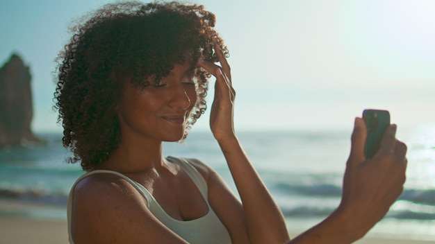 Uśmiechnięta dziewczyna pozuje smartphone co selfie na plaży z bliska Portret kobiety