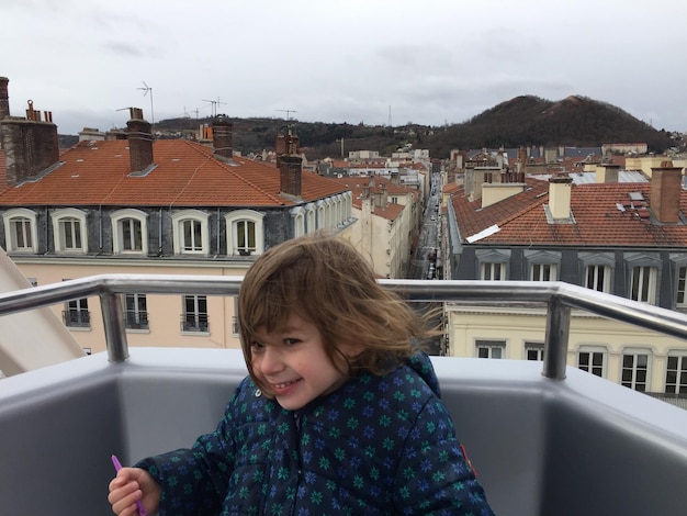 Zdjęcie uśmiechnięta dziewczyna stojąca na balkonie na tle nieba
