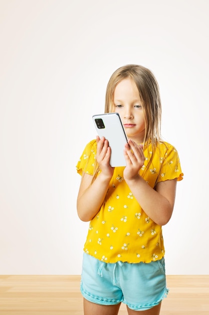 Uśmiechnięta dziewczynka dzwoni na smartfon w domu ludzie dzieci technologia i koncepcja komunikacji