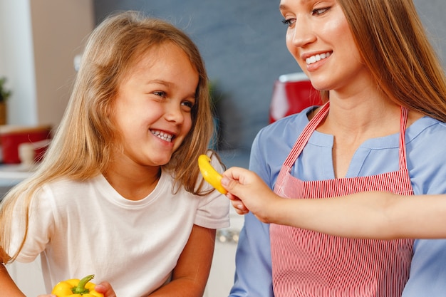 Uśmiechnięta dziewczynka pomaga matce w kuchni