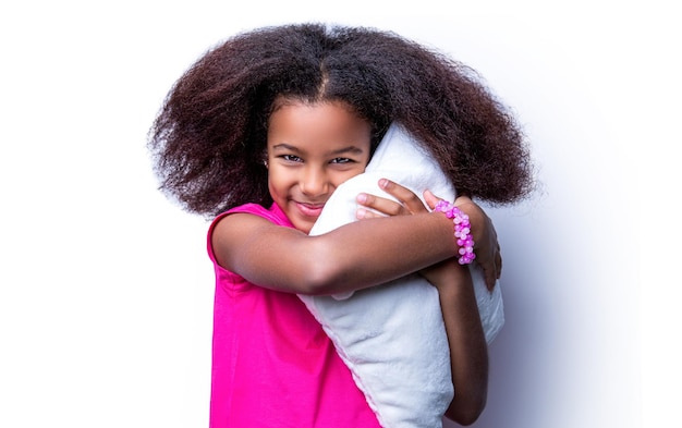 Uśmiechnięta dziewczynka trzyma poduszkę Uśmiech mała dziewczynka Afroamerykanów trzyma pocałunek Rano mała dziewczynka poduszka poduszka pocałunek Dzieci dziewczyna trzyma poduszkę na białym tle
