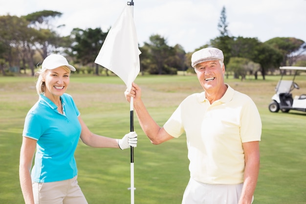 Uśmiechnięta golfista para trzyma białą flaga