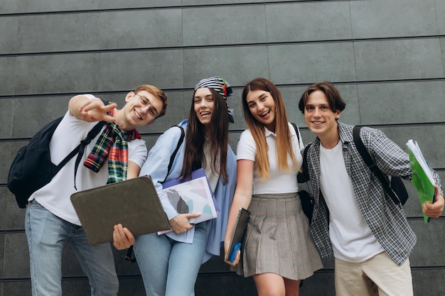 Zdjęcie uśmiechnięta grupa studentów trzymających zeszyty i zeszyty do nauki szczęśliwi przyjaciele koncepcja uczenia się skopiuj miejsce