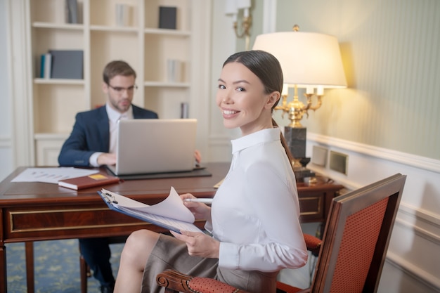 Uśmiechnięta i pewna siebie kobieta pracująca w biurze