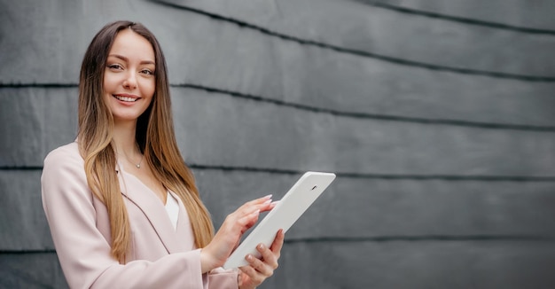 Uśmiechnięta kaukaska bizneswoman stojąca i trzymająca tabletkę