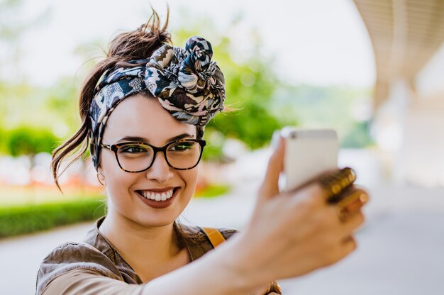 Uśmiechnięta kobieta bierze selfie fotografię w miastowej ulicie