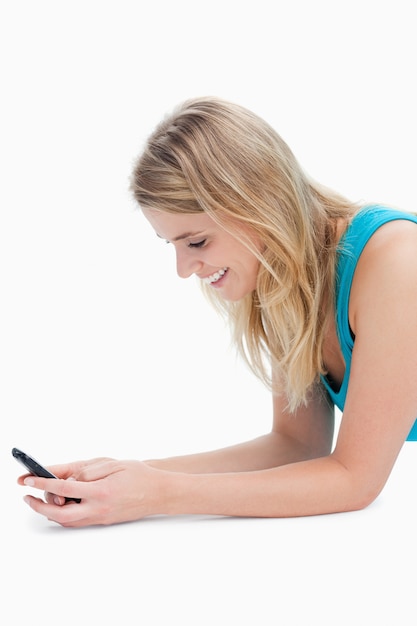 Uśmiechnięta kobieta jest SMS-y na jej telefon komórkowy