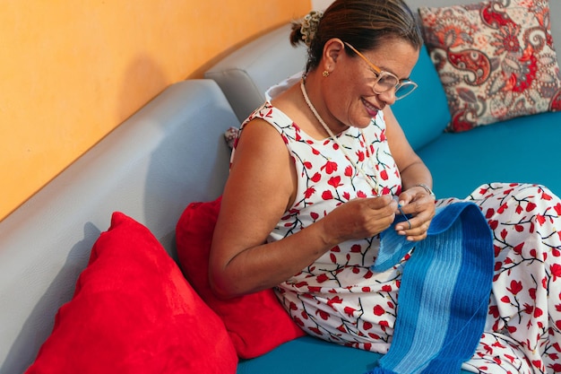 Uśmiechnięta kobieta na kanapie robi na drutach