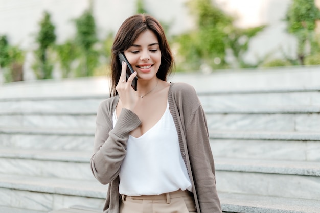 Uśmiechnięta kobieta opowiada na telefonie outdoors