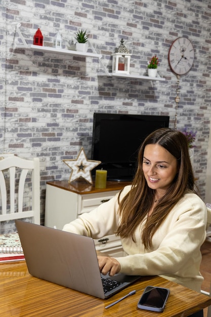 Uśmiechnięta kobieta pisze z domu na laptopie