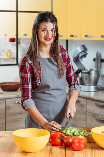 Uśmiechnięta kobieta przygotowuje warzywa w kitche