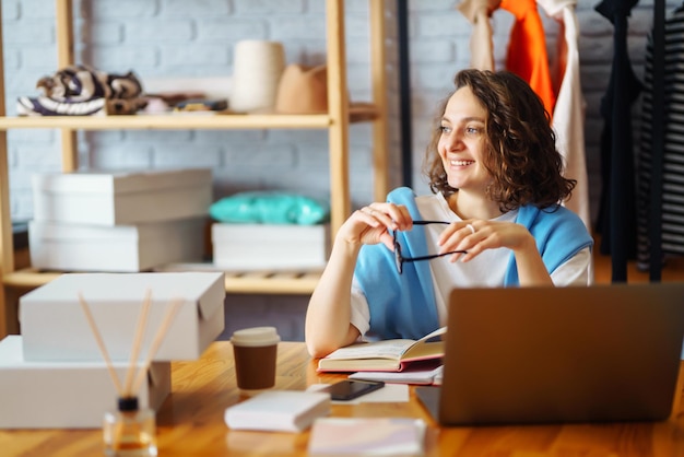 Uśmiechnięta kobieta robi notatki z zamówień z laptopa Właściciel Dropshipping pracuje