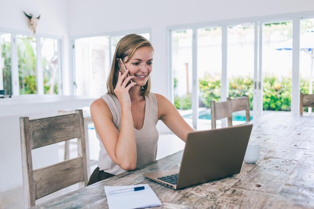 Uśmiechnięta kobieta rozmawia przez telefon w domu