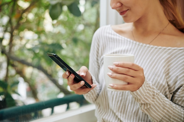 Uśmiechnięta kobieta sprawdza swój telefon