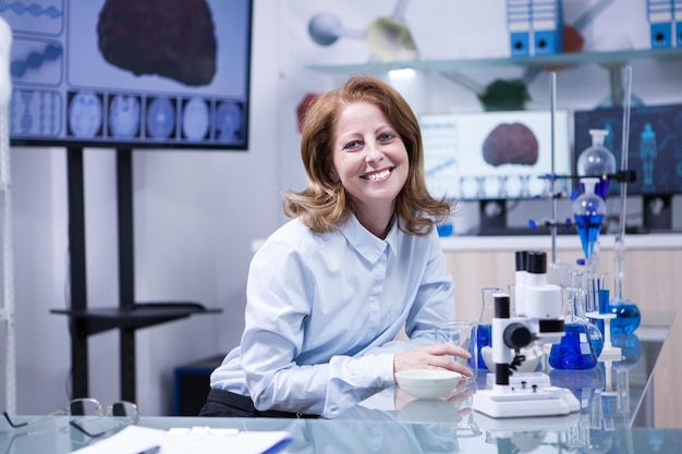 Uśmiechnięta kobieta starszy lekarz pracujący z mikroskopem w laboratorium. Współczesny naukowiec.