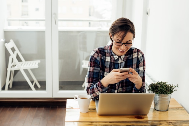 Uśmiechnięta kobieta texting na jej telefonie komórkowym wysyła sms wiadomość