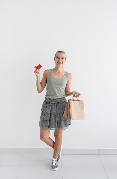 Uśmiechnięta kobieta trzymająca ekologiczne torby na zakupy i kartę kredytową