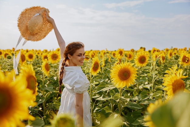 Uśmiechnięta kobieta w kapeluszu polnym słonecznika w rękach krajobraz przyrody