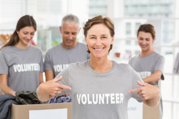 Uśmiechnięta kobieta wolontariusz wskazuje na koszula
