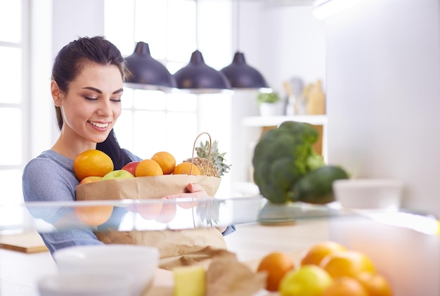Uśmiechnięta kobieta wyciągająca świeże owoce z lodówki koncepcja zdrowej żywności