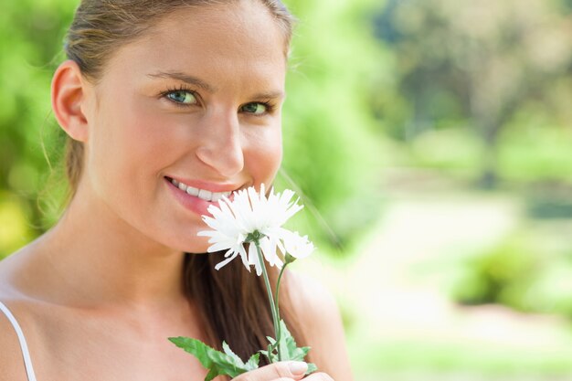 Uśmiechnięta kobieta z kwiatem w parku