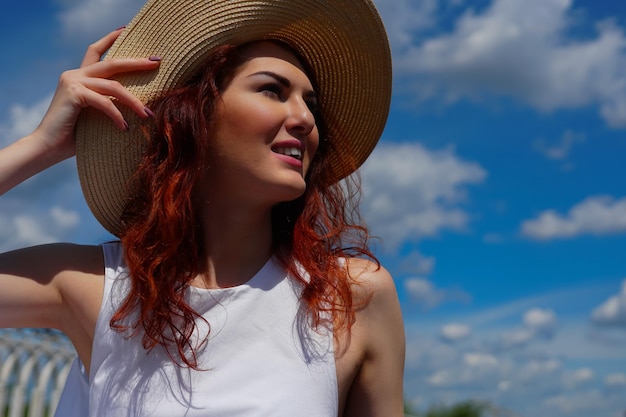 Uśmiechnięta kobieta z pięknymi rudymi włosami w kapeluszu