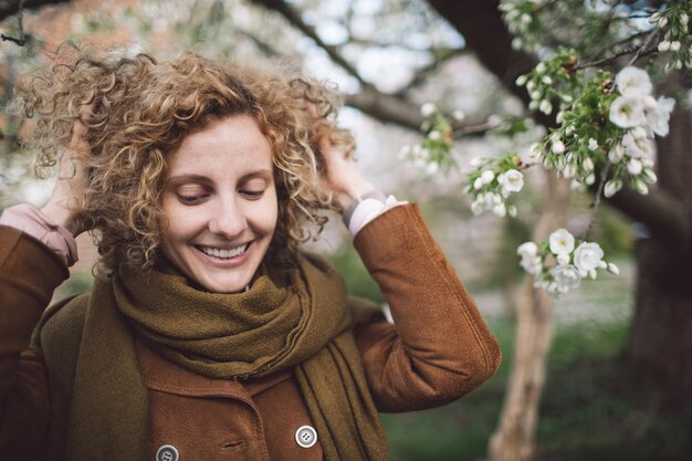 Zdjęcie uśmiechnięta kobieta z rękami w włosach w parku