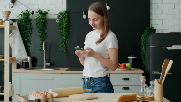 Uśmiechnięta kobieta za pomocą inteligentnego telefonu w kuchni