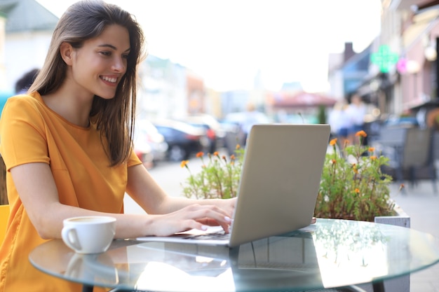 Uśmiechnięta kobieta za pomocą laptopa w kawiarni. Pojęcie przedsiębiorcy, businesswoman, freelancer.