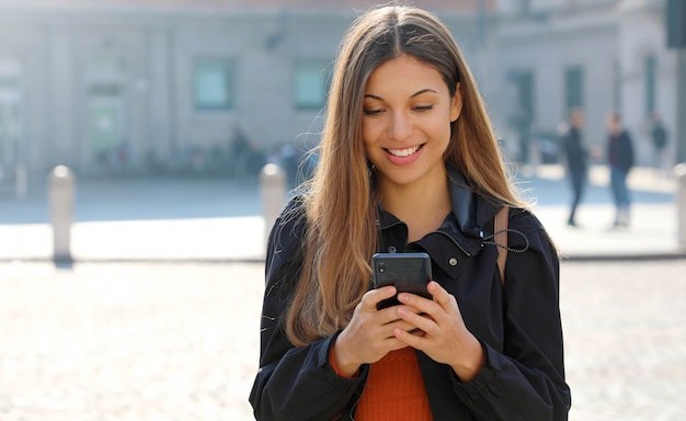 Uśmiechnięta kobieta za pomocą swojego smartfona