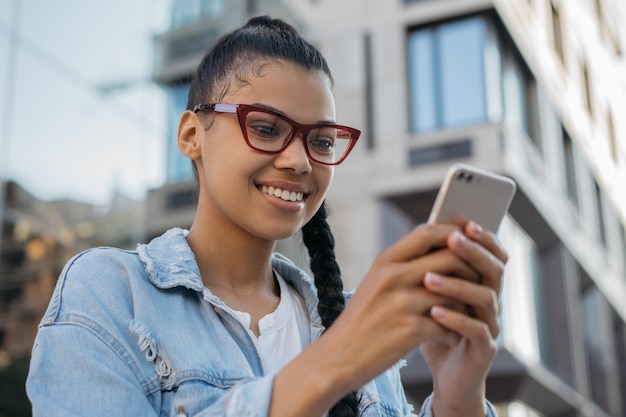 Uśmiechnięta kobieta za pomocą wiadomości tekstowych komunikacji telefonu komórkowego o połączenie wideo