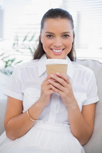 Uśmiechnięta ładna kobieta ma kawowego obsiadanie na wygodnej leżance