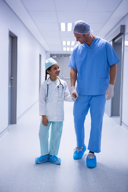 Uśmiechnięta lekarka i dziewczyna oddziała wzajemnie podczas gdy chodzący w korytarzu