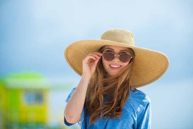Uśmiechnięta letnia kobieta w kapeluszu i okularach przeciwsłonecznych