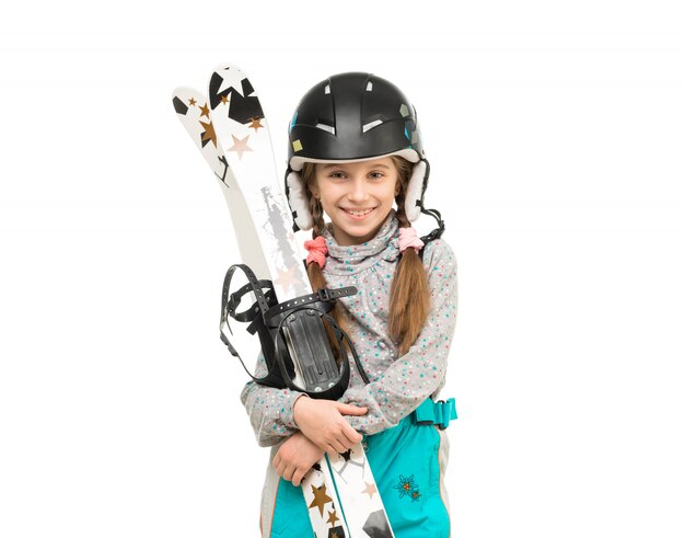 Uśmiechnięta mała dziewczynka w hełma mienia nartach
